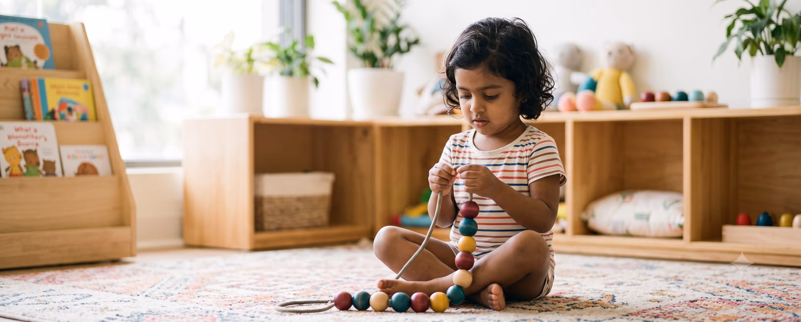 A child threading colourful wooden beads during an occupational therapy activity.