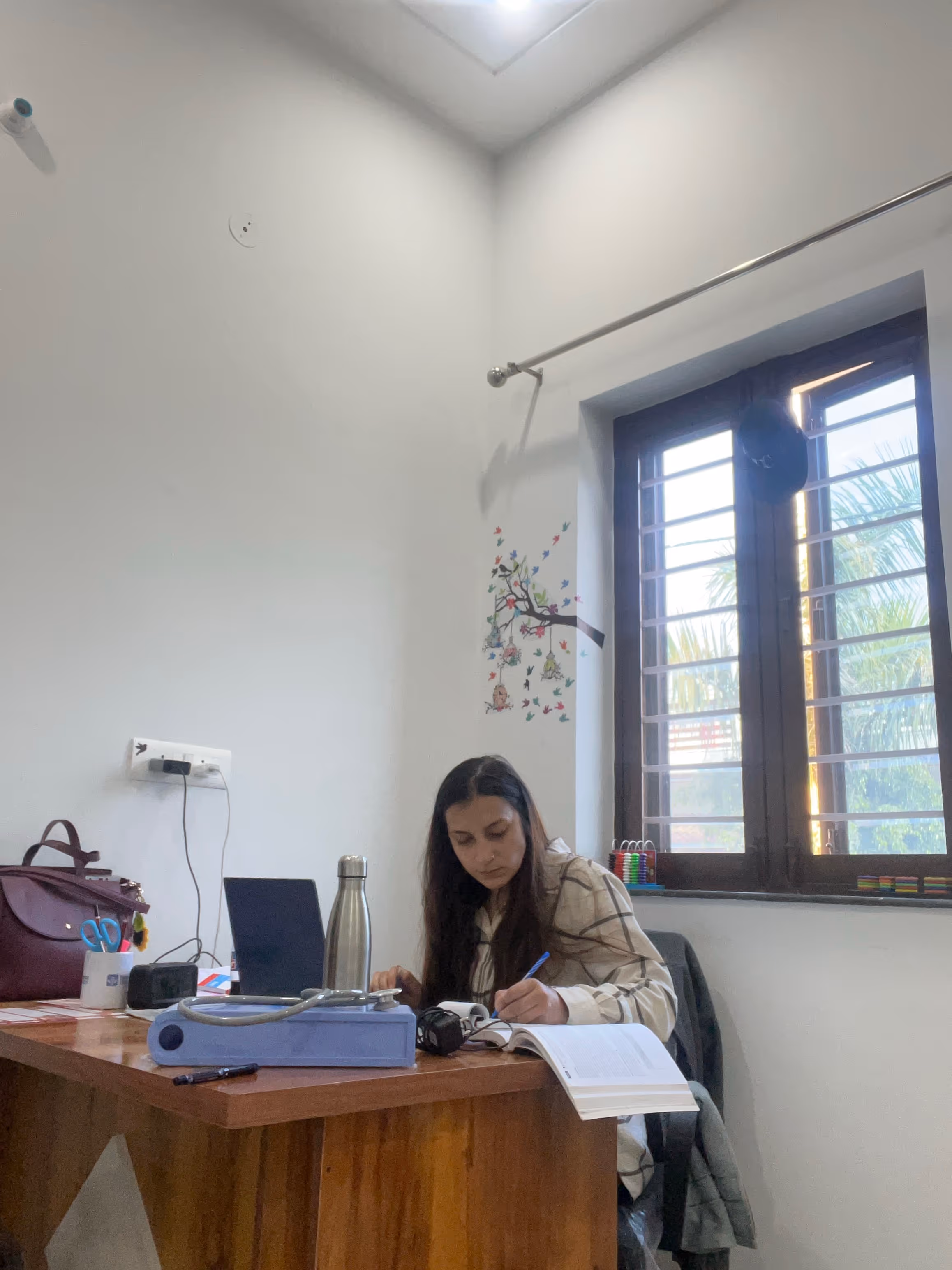 A therapist reviewing notes at her desk in a consultation room at Kiddicove Dehradun.